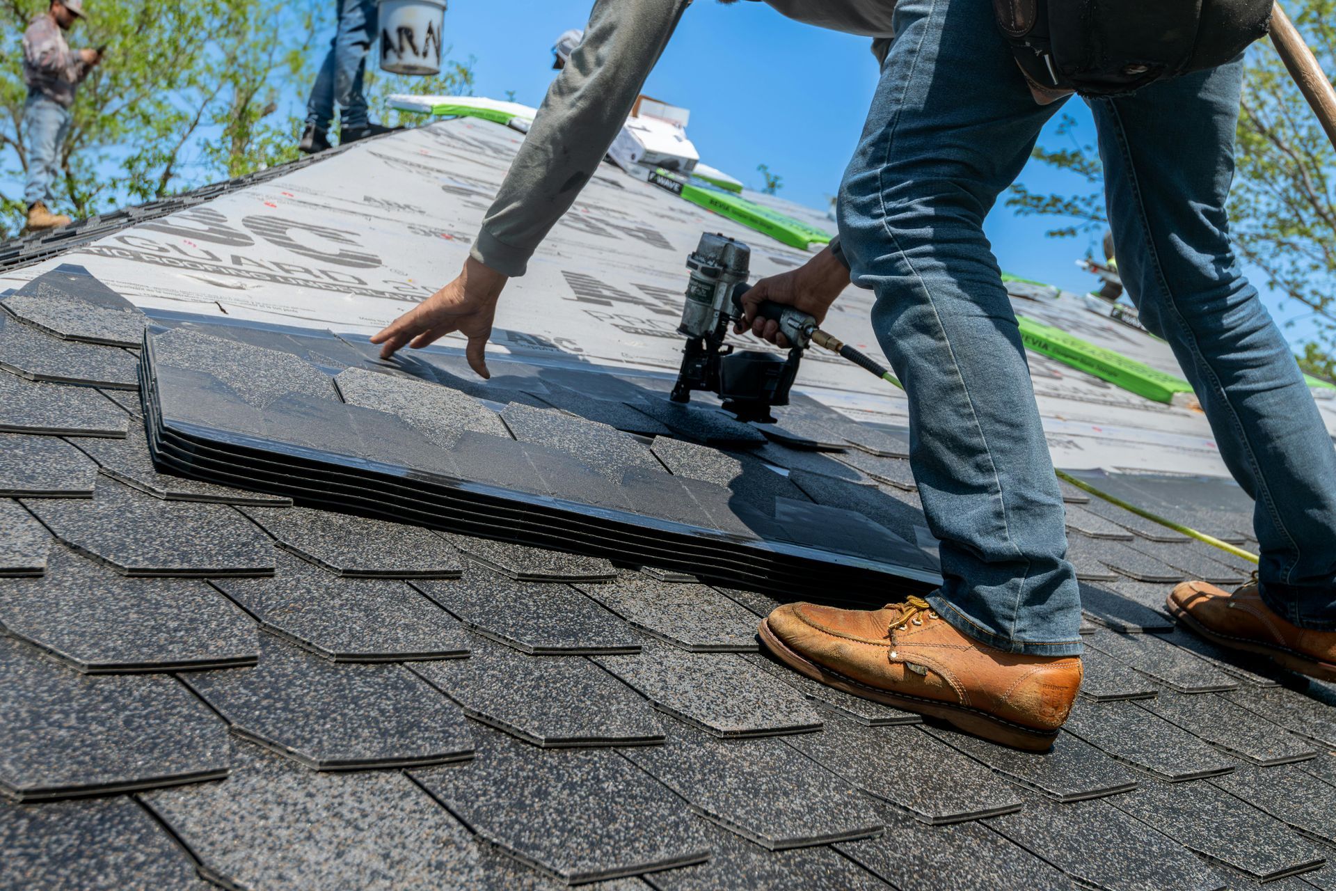 A worker installing shingles on a roof.
